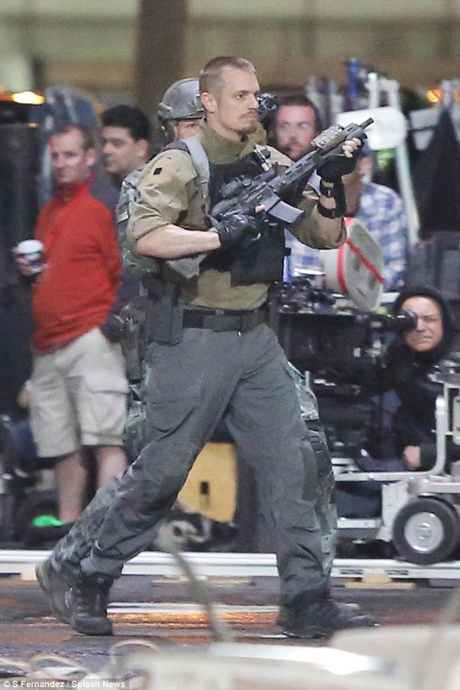 Action man: Joel Kinnaman looked ready for a fight as he held his gun in the air